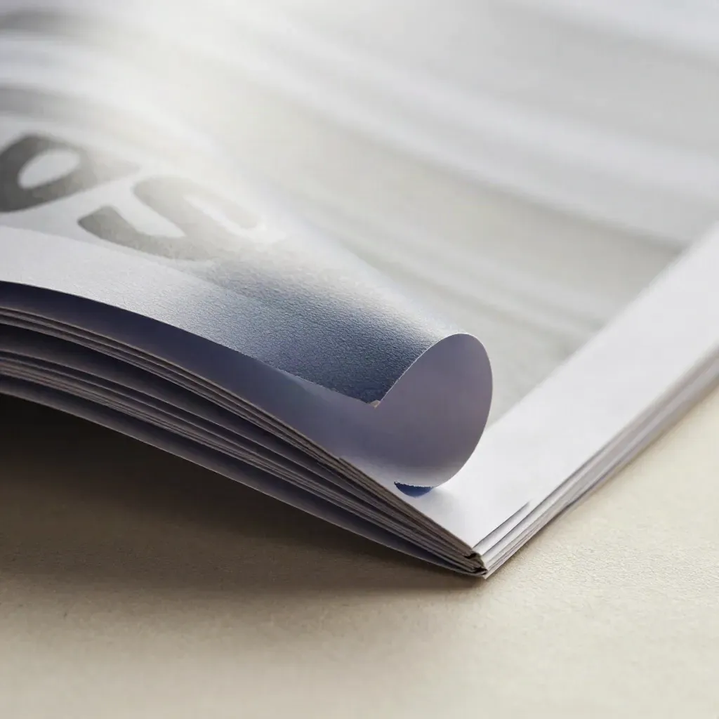 Macro of layered banner materials curling against a bright studio gradient.